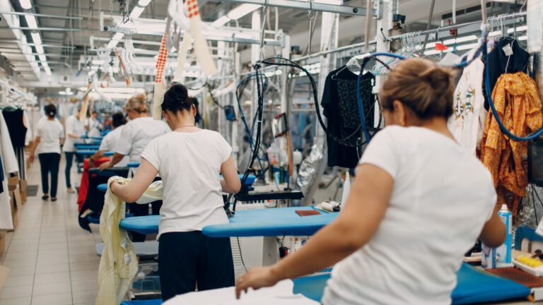 Factory scene with women sorting and arranging clothes on racks