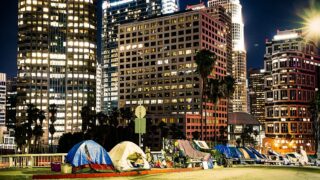 Tents set up for the night with a backdrop of Los Angeles high-rise buildings.
