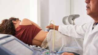 Doctor examining the woman's right kidney using an ultrasound scanner.