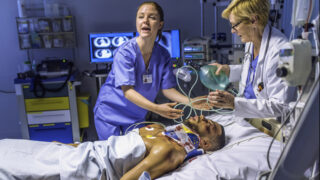 Female doctor holding a resuscitation bag on the face of a patient in emergency room.