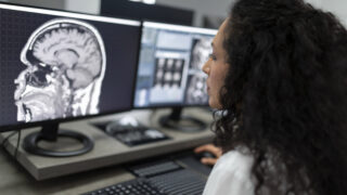 Close-up of female radiologist looking at the MRI image of the head on her monitor and analysing it.